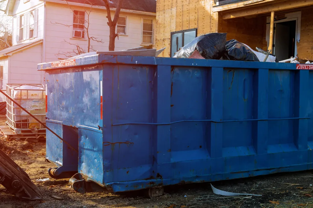 Dumpster loaded with roofing shingles and debris